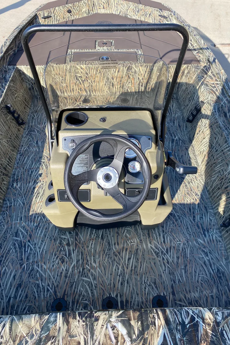 Slide: The Image of 2025 Tracker Grizzly 1860 CC boat interior with camouflage design and steering console. - 6