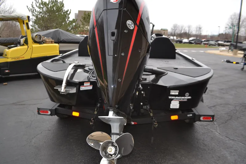 Slide: The Image of 2025 Tracker Savage 215 boat, rear view with motor and trailer, parked outdoors. - 2