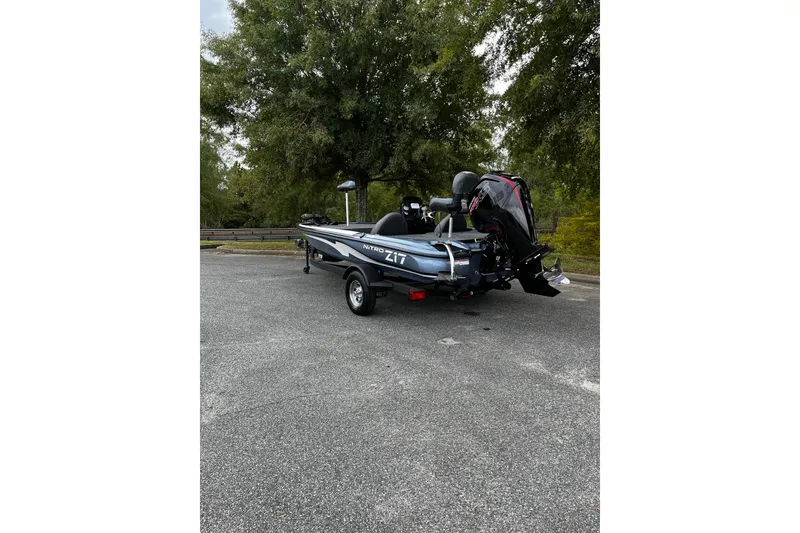 Slide: The Image of 2025 Nitro Z17 boat parked on asphalt, surrounded by trees. - 2