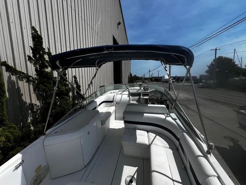 Slide: The Image of 2000 Formula 260 Sun Sport boat with canopy, docked beside a building under clear skies. - 5