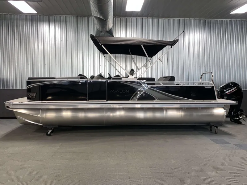 Slide: The Image of 2025 Avalon LSZ 2385 VRB Tritoon boat in showroom, sleek design, black canopy. - 18
