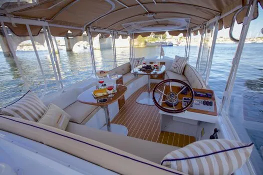 Slide: The Image of 2022 Duffy Back Bay 16 boat interior with elegant seating and dining setup on the water. - 16