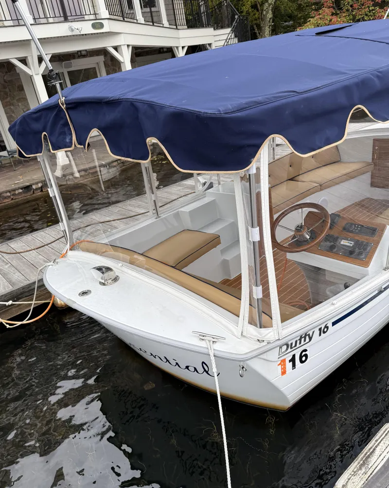 Slide: The Image of 2022 Duffy Back Bay 16 boat with blue canopy docked at marina. - 6