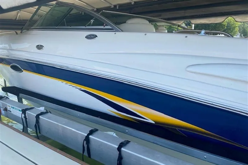 Slide: The Image of 2003 Chaparral 260 SSi boat with blue and yellow accents, docked under a canopy. - 19