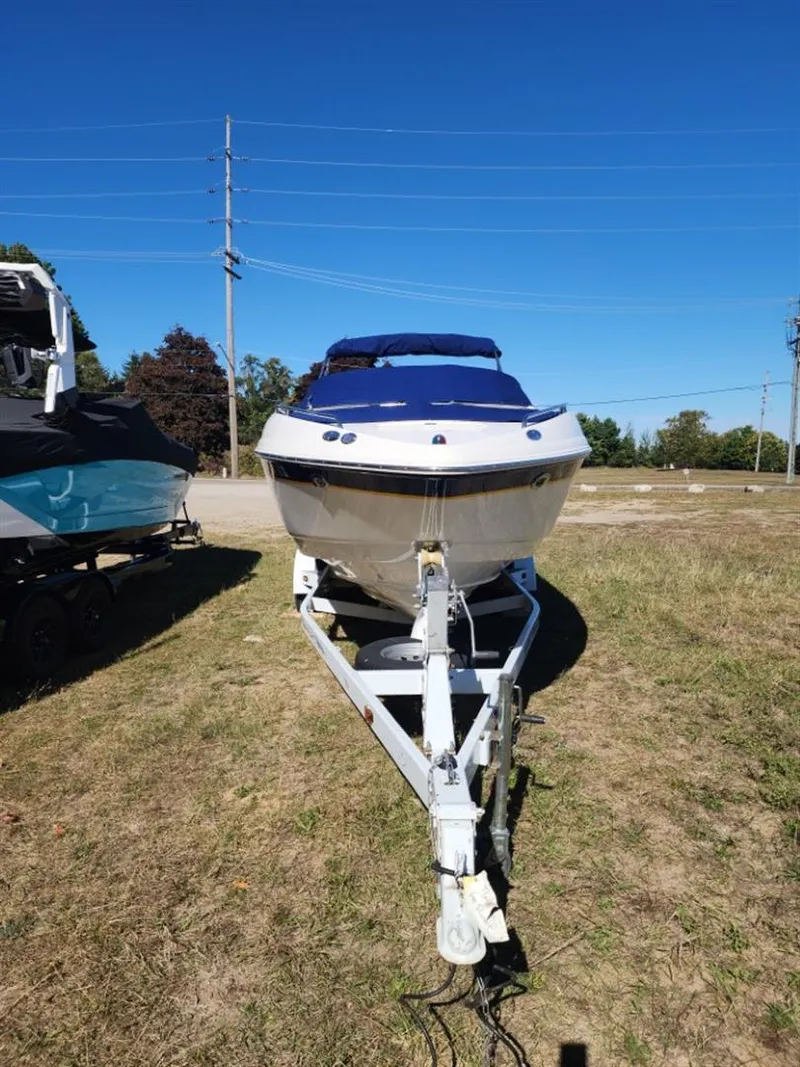 Slide: The Image of 2003 Chaparral 260 SSi boat on trailer, parked on grassy area under clear blue sky. - 9