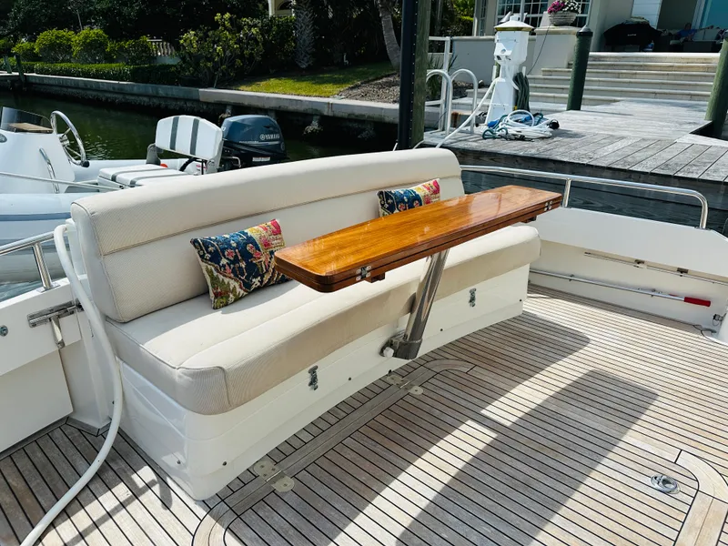 Slide: The Image of 2014 Grand Banks 46 Eastbay SX yacht with cushioned seating and wooden table on deck. - 10