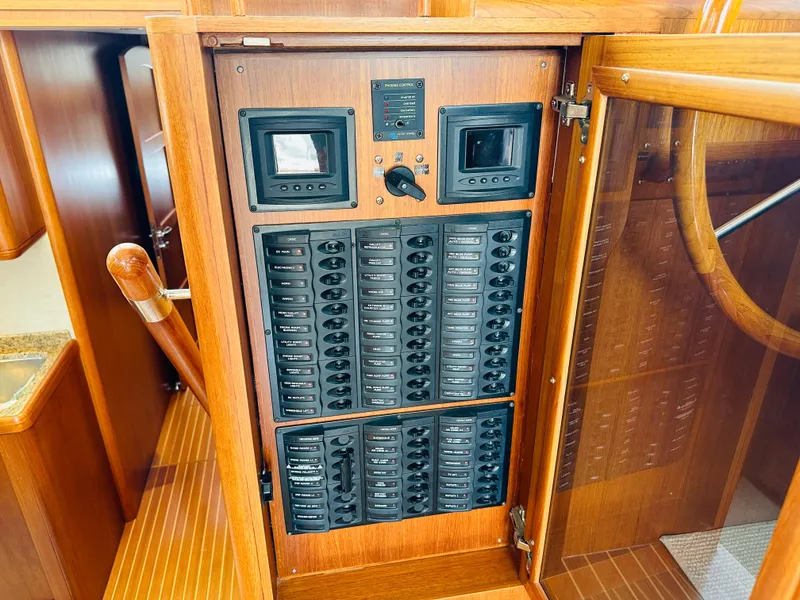 Slide: The Image of Electrical panel inside 2014 Grand Banks 46 Eastbay SX yacht, featuring wooden cabinetry and control switches. - 32