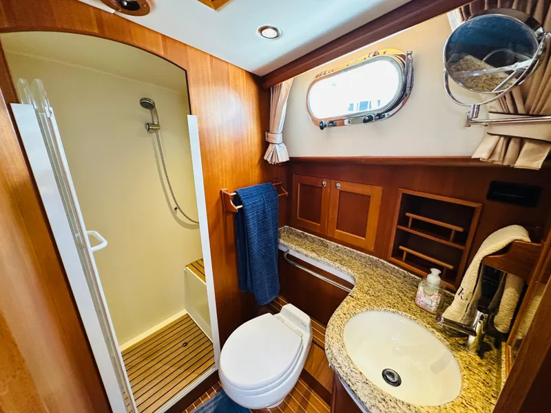 Slide: The Image of Luxurious 2014 Grand Banks 46 Eastbay SX yacht bathroom with shower, sink, and wooden cabinetry. - 47