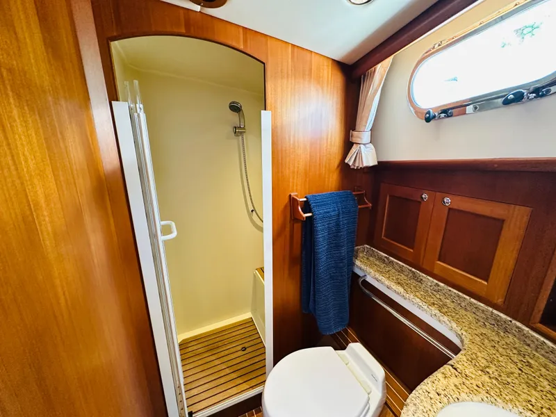 Slide: The Image of 2014 Grand Banks 46 Eastbay SX yacht bathroom with shower, wooden cabinetry, and granite countertop. - 48