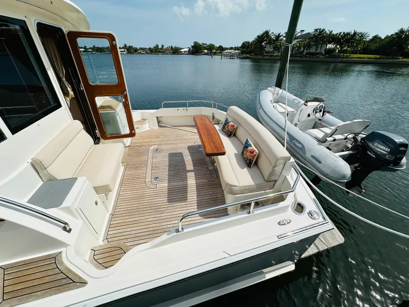 Slide: The Image of 2014 Grand Banks 46 Eastbay SX yacht with spacious deck and tender on calm water. - 6