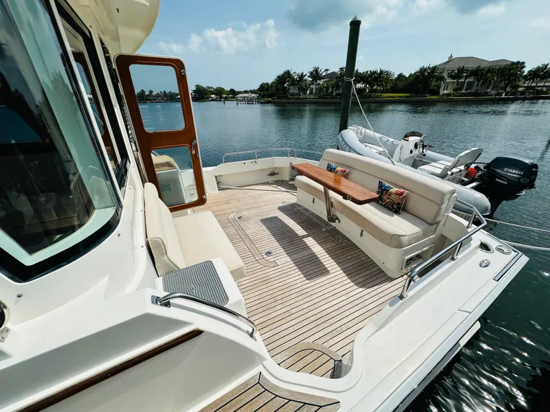 Slide: The Image of 2014 Grand Banks 46 Eastbay SX yacht deck with seating, docked by serene waterfront. - 7
