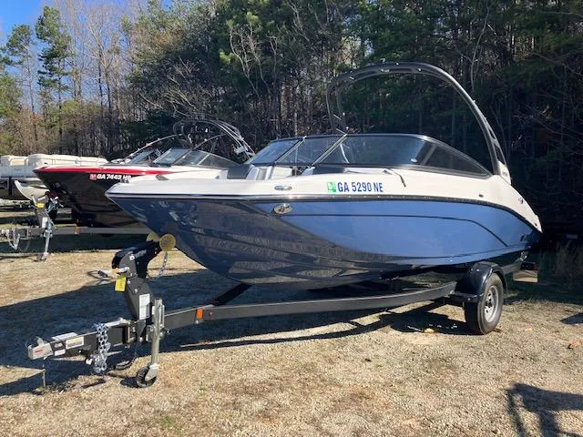 Slide: The Image of 2024 Yamaha Boats 195S on trailer, parked outdoors, surrounded by trees. - 0