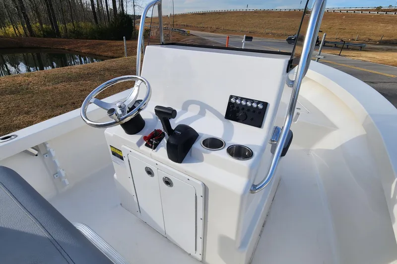 Slide: The Image of 2025 May-Craft 192 CC boat console with steering wheel and controls, parked near a pond. - 9
