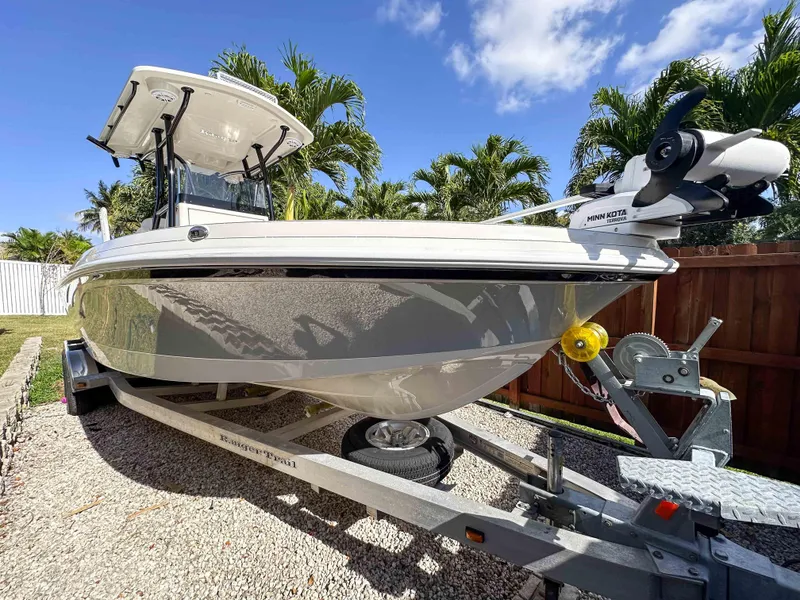 Slide: The Image of 2023 Ranger 2360 Bay boat on trailer, parked outdoors under clear blue sky. - 0