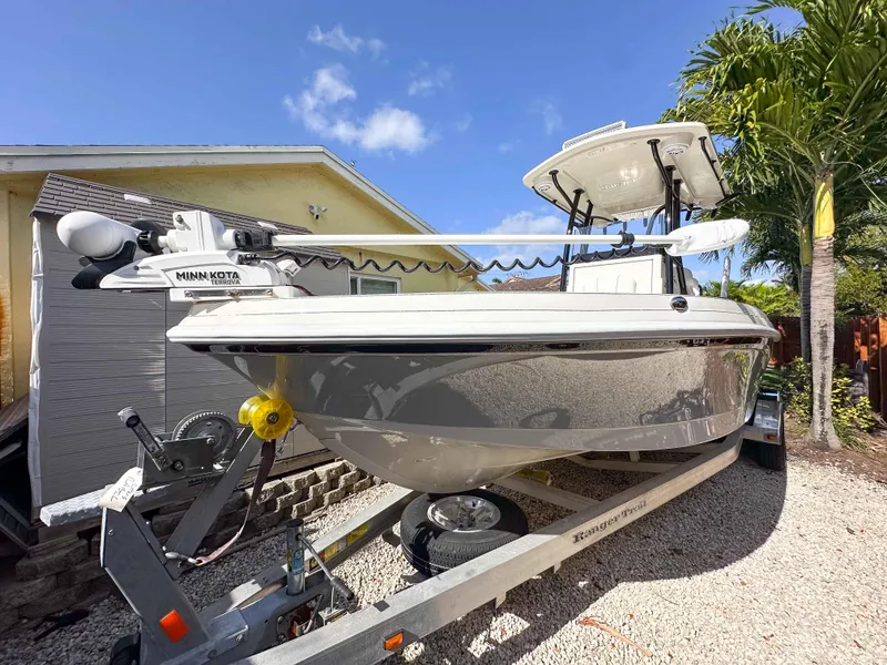 Slide: The Image of 2023 Ranger 2360 Bay boat on trailer, parked outdoors under clear blue sky. - 1
