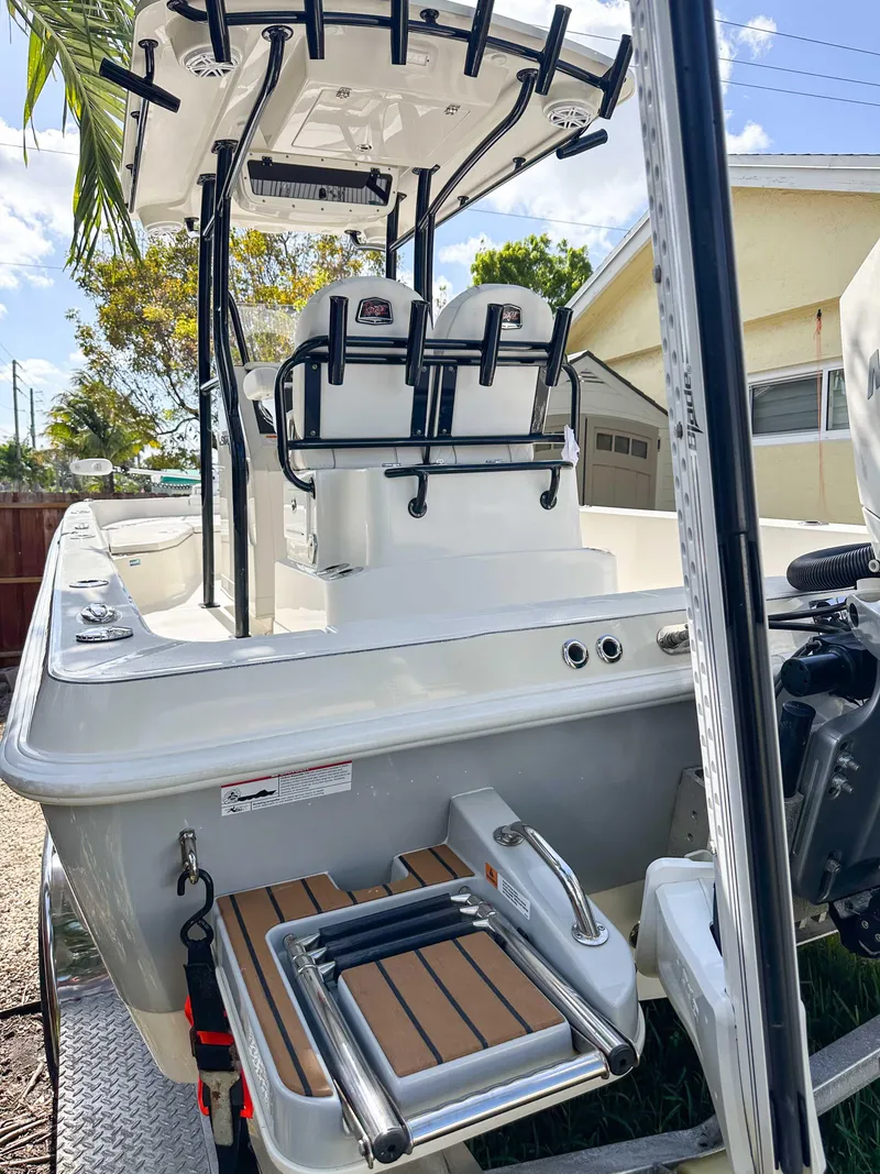 Slide: The Image of 2023 Ranger 2360 Bay boat with fishing rod holders and swim platform, parked outdoors. - 12