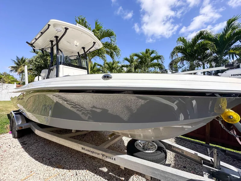 Slide: The Image of 2023 Ranger 2360 Bay boat on trailer, surrounded by palm trees under a blue sky. - 2