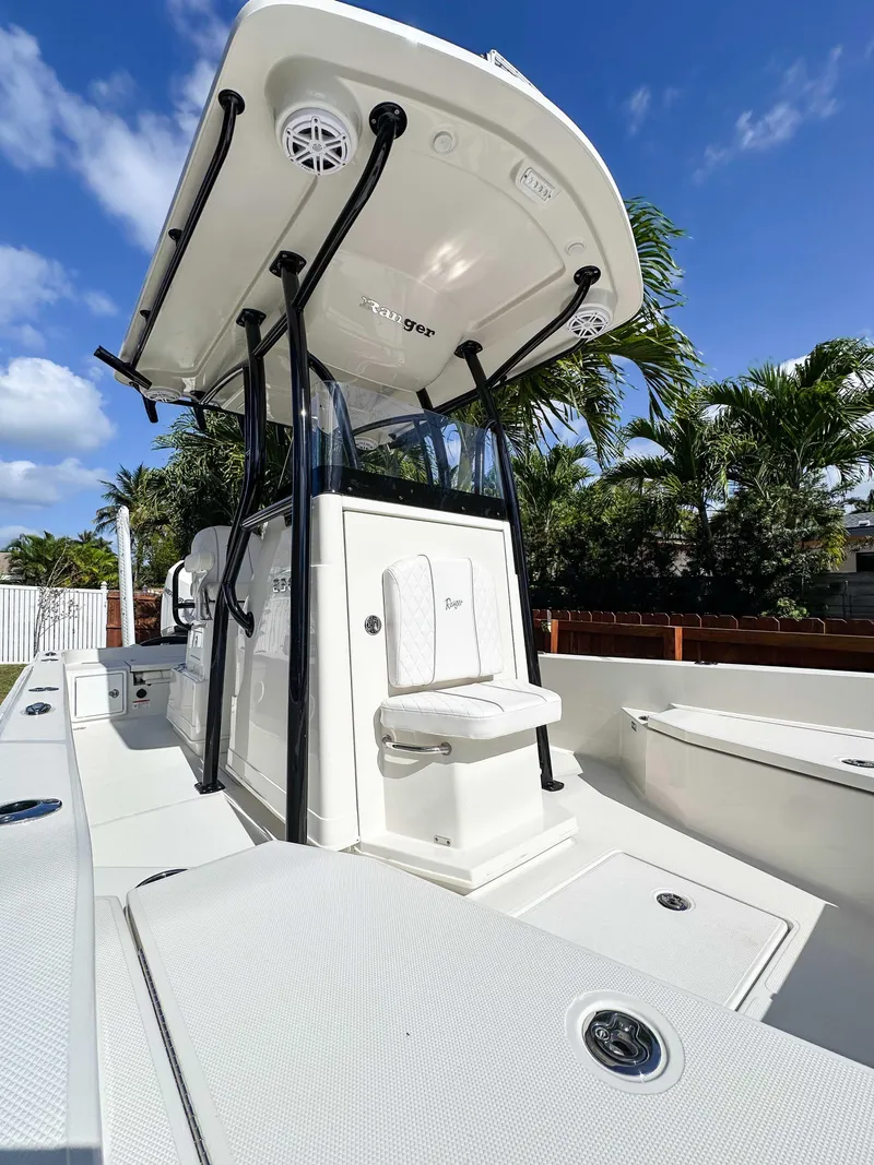 Slide: The Image of 2023 Ranger 2360 Bay boat with T-top, white deck, and seating, under clear blue sky. - 20