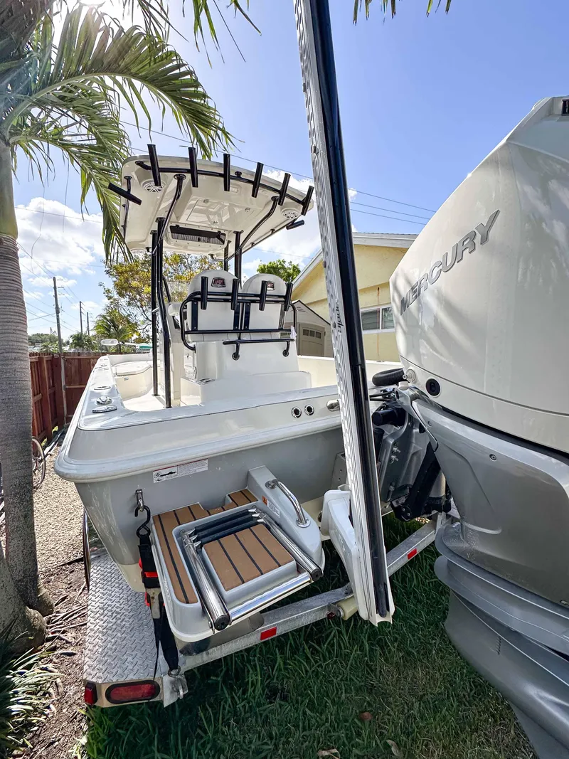 Slide: The Image of 2023 Ranger 2360 Bay boat with Mercury engine, parked outdoors near palm trees. - 23