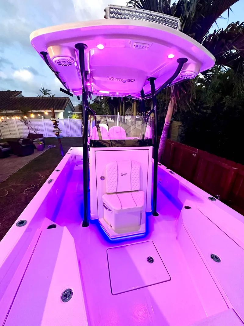 Slide: The Image of 2023 Ranger 2360 Bay boat with vibrant purple LED lighting, docked outdoors. - 29