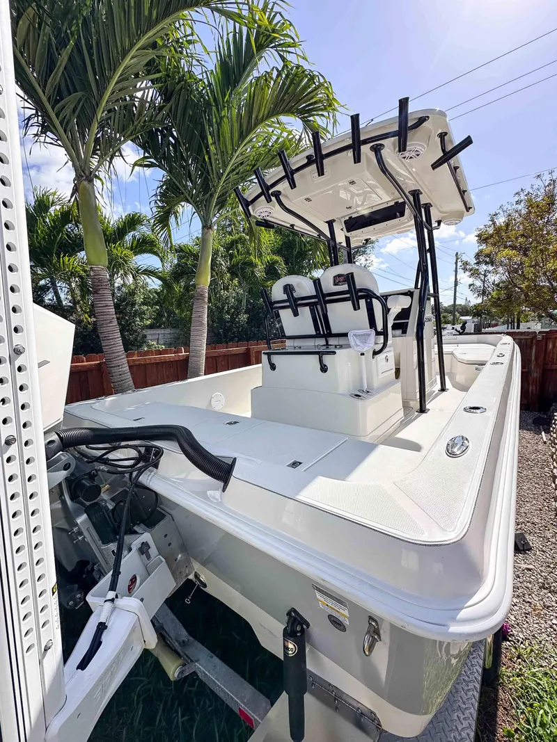 Slide: The Image of 2023 Ranger 2360 Bay boat with T-top, parked outdoors under palm trees. - 6