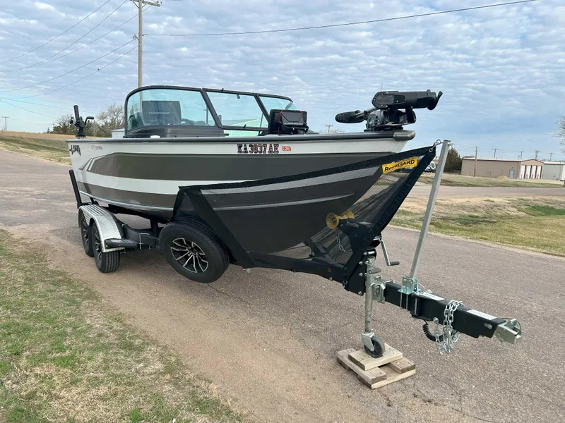 Slide: The Image of 2024 Lund 1875 Fisherman boat on trailer, parked on roadside under cloudy sky. - 3