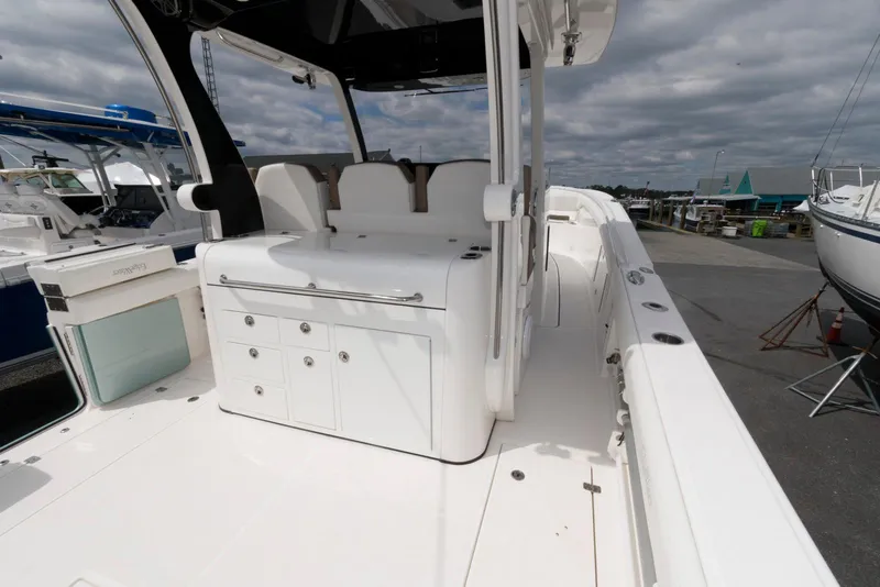 Slide: The Image of 2017 Edgewater 368CC boat interior with seating and storage, docked under cloudy skies. - 11