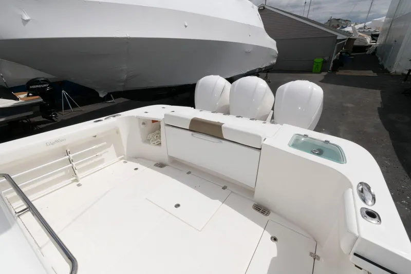 Slide: The Image of 2017 Edgewater 368CC boat deck with triple outboard engines, docked in a marina. - 12