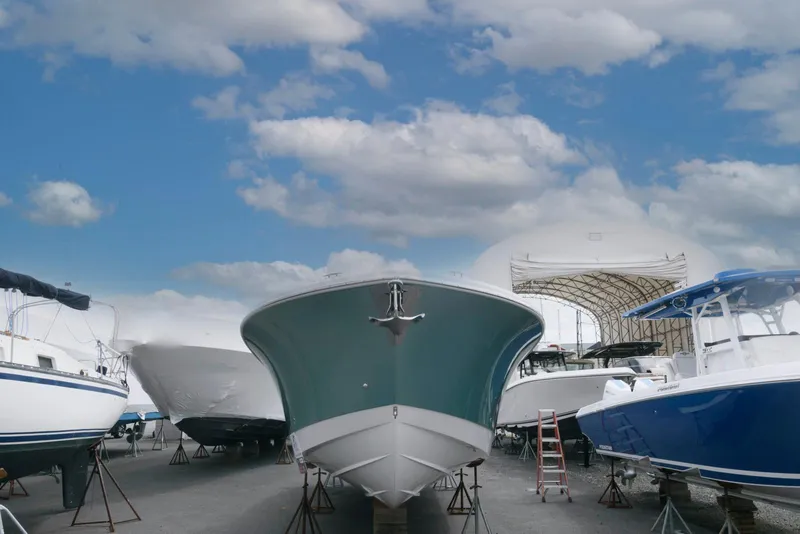 Slide: The Image of 2017 Edgewater 368CC boat in a marina, surrounded by other vessels under a cloudy sky. - 3