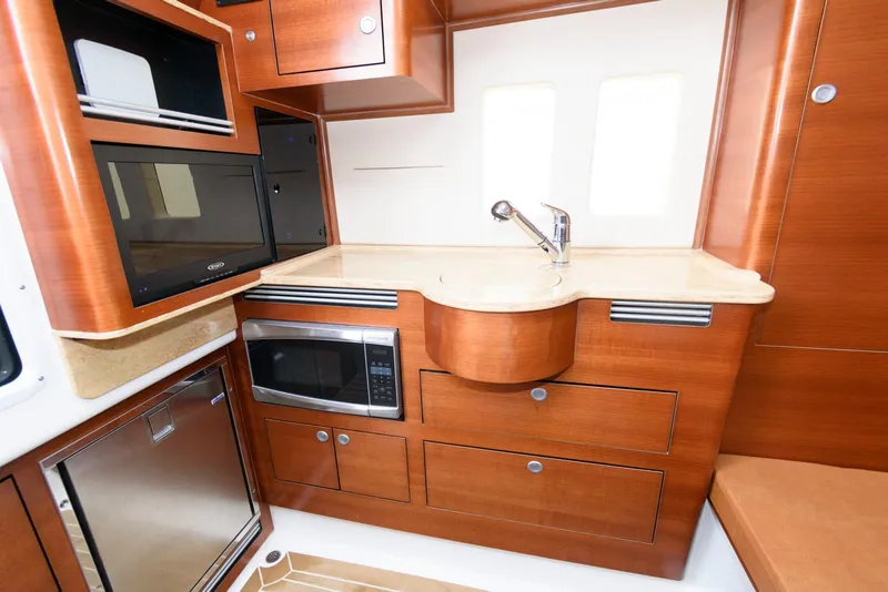 Slide: The Image of 2017 Edgewater 368CC boat kitchen with wood cabinetry, microwave, and sink. - 34