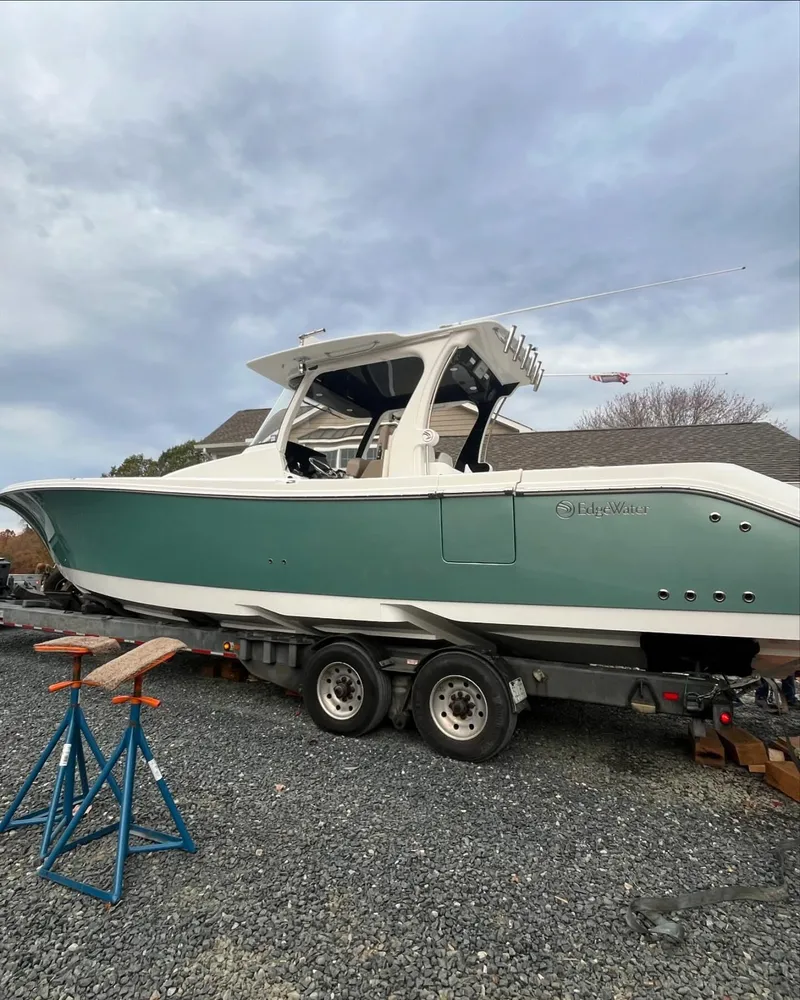 Slide: The Image of 2017 Edgewater 368CC boat on trailer, parked on gravel under cloudy sky. - 4