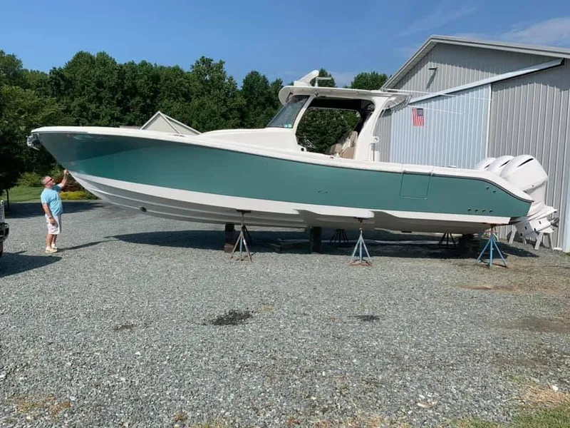 Slide: The Image of 2017 Edgewater 368CC boat on stands, outdoors near a metal building. - 5