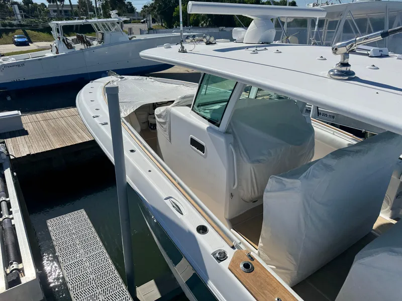 Slide: The Image of 2020 HCB 42 Lujo boat docked, featuring covered seating and sleek design. - 3