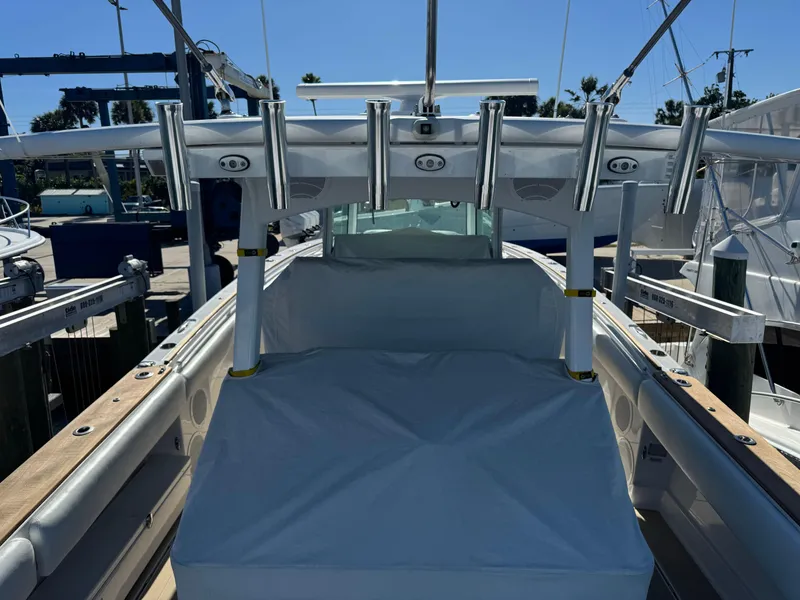 Slide: The Image of 2020 HCB 42 Lujo boat with rod holders and covered seating area at a marina. - 4