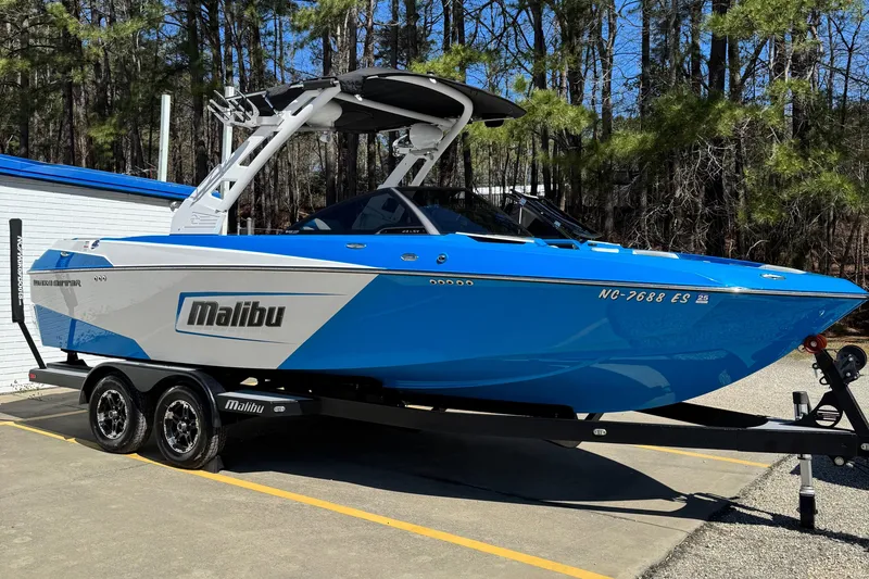 Slide: The Image of 2019 Malibu Wakesetter 23 LSV boat on trailer, blue and white, parked outdoors. - 1