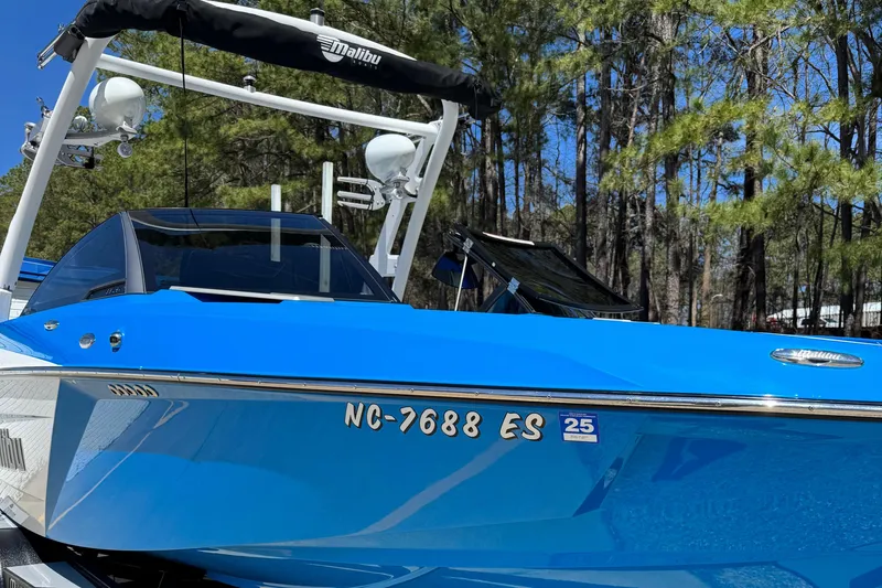 Slide: The Image of 2019 Malibu Wakesetter 23 LSV boat in vibrant blue, docked near trees. - 2