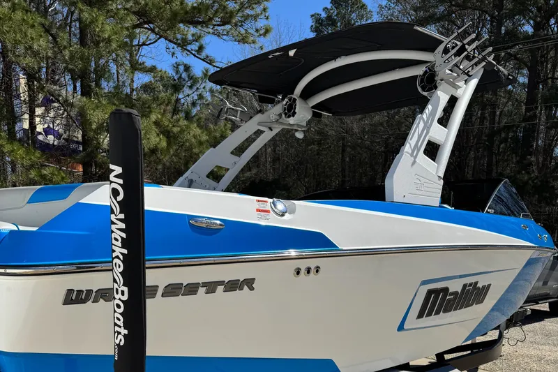Slide: The Image of 2019 Malibu Wakesetter 23 LSV boat with blue and white design, parked outdoors. - 5