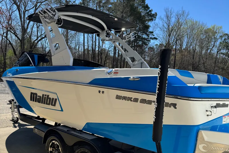 Slide: The Image of 2019 Malibu Wakesetter 23 LSV boat in blue and white, parked outdoors. - 6