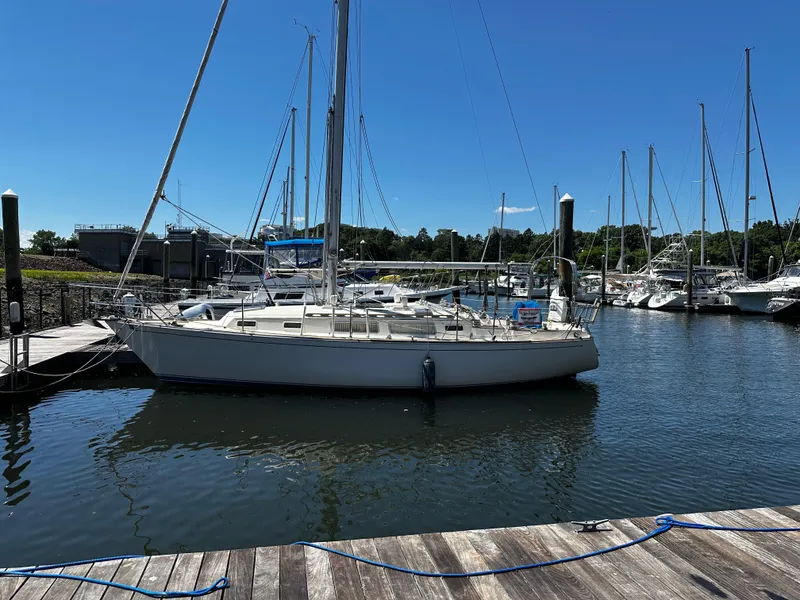 The Image of 1985 Sabre 32 Aft Cabin sailboat docked in a marina under clear blue sky. - 0