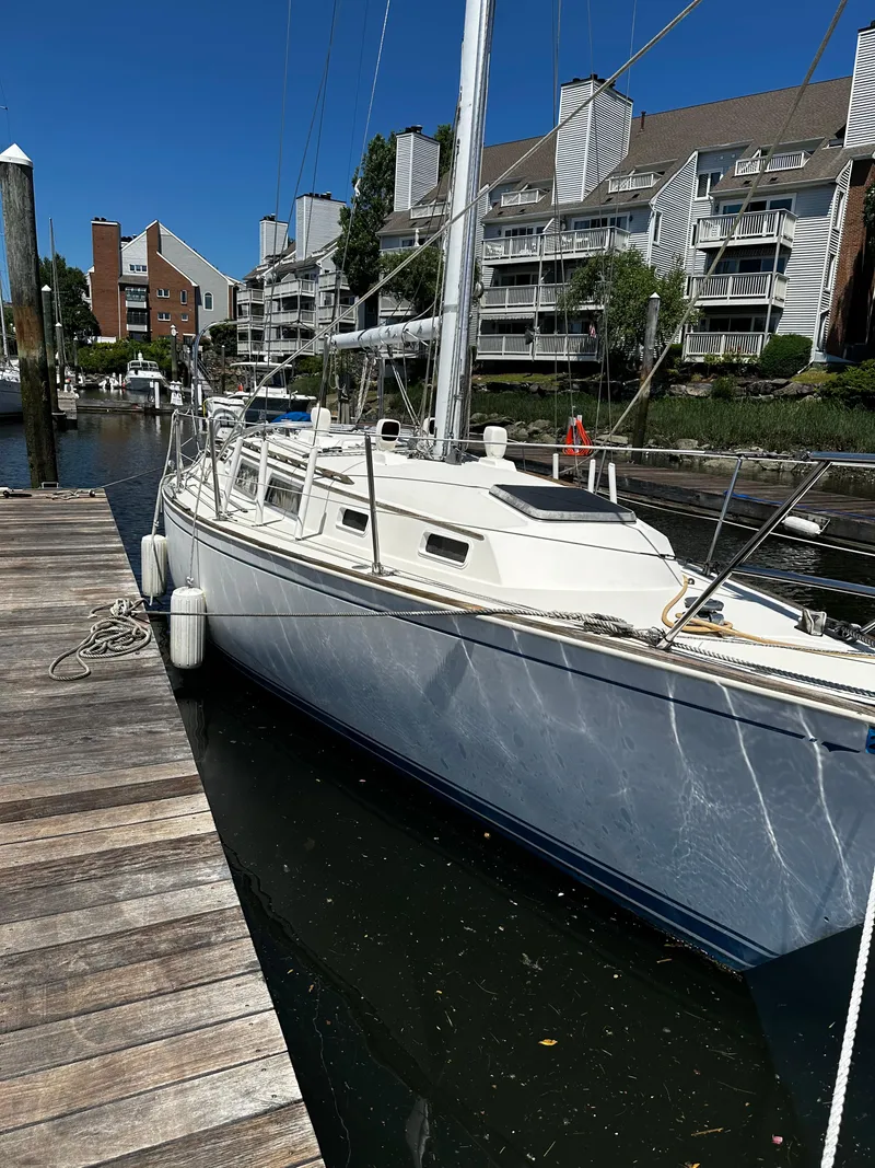 Slide: The Image of 1985 Sabre 32 Aft Cabin sailboat docked in a marina, surrounded by modern buildings. - 1