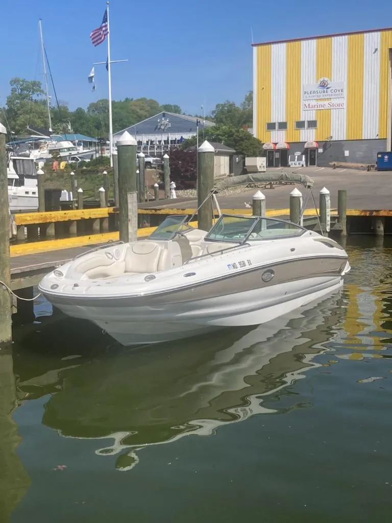 Slide: The Image of 2006 Crownline 262 EX boat docked at a marina with a yellow-striped building. - 2
