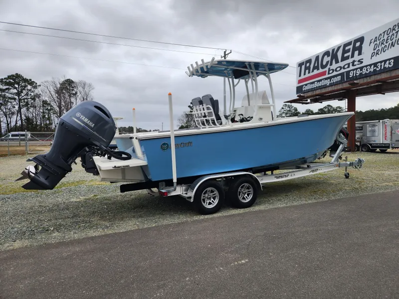 Slide: The Image of 2025 May-Craft 245 Offshore CC boat on trailer, blue hull, Yamaha outboard motor, parked outdoors. - 2