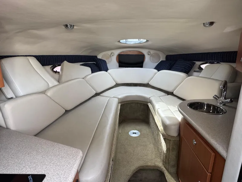 Slide: The Image of Interior of 2008 Crownline 315 SCR boat with plush seating and compact kitchenette. - 17