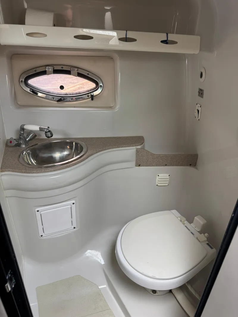 Slide: The Image of 2008 Crownline 315 SCR boat bathroom with sink, toilet, and porthole window. - 21