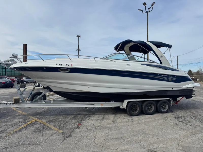 Slide: The Image of 2008 Crownline 315 SCR boat on trailer in parking lot, blue and white design. - 25