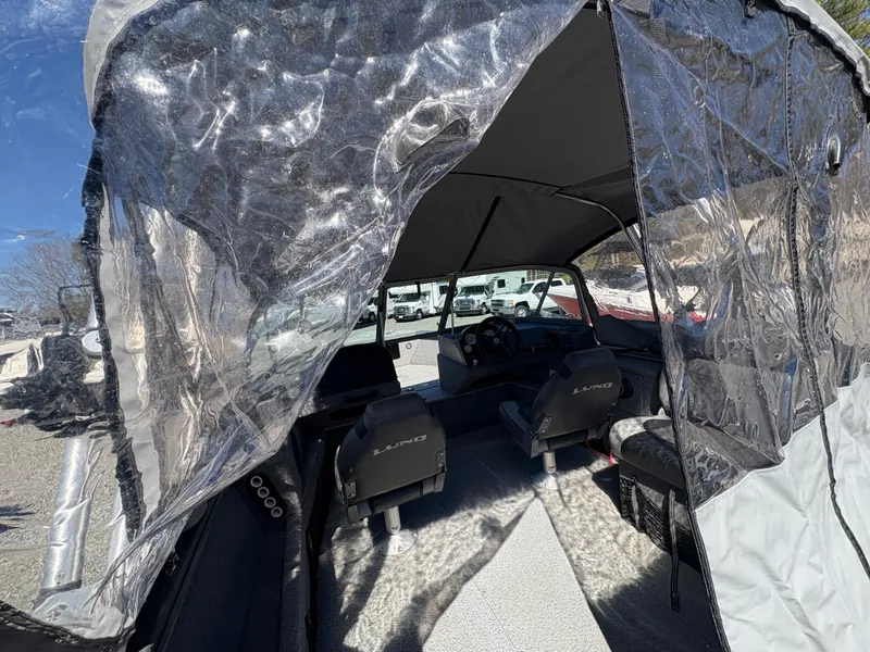 Slide: The Image of 2017 Lund 1800 Sport Angler interior with protective cover, showcasing seating and steering area. - 11