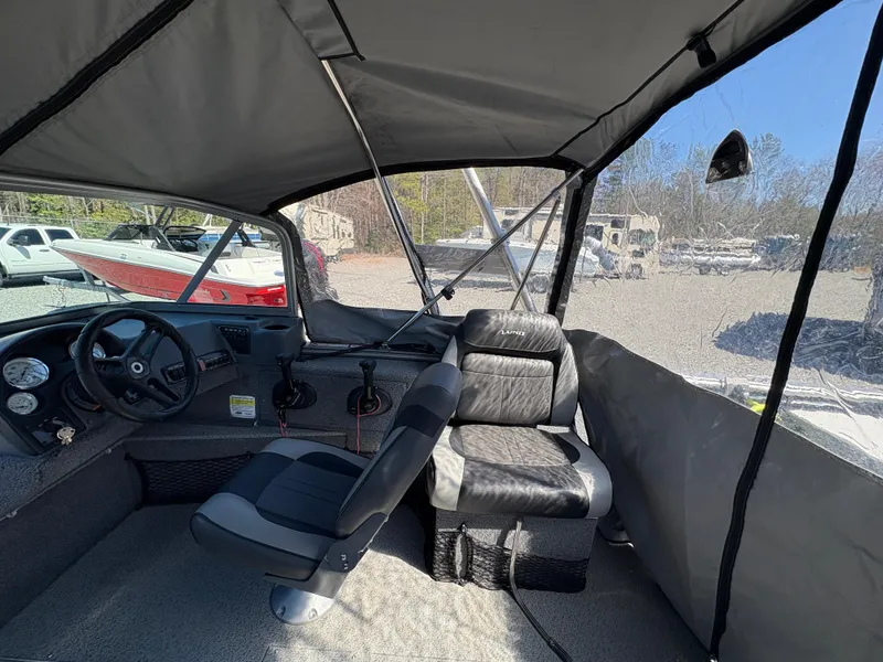 Slide: The Image of 2017 Lund 1800 Sport Angler interior with seating and dashboard, parked outdoors. - 13