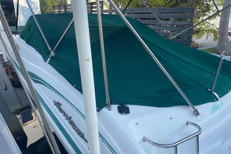 Slide: The Image of Covered 2000 Hurricane SunDeck 237 OB boat with green tarp and railing. - 15