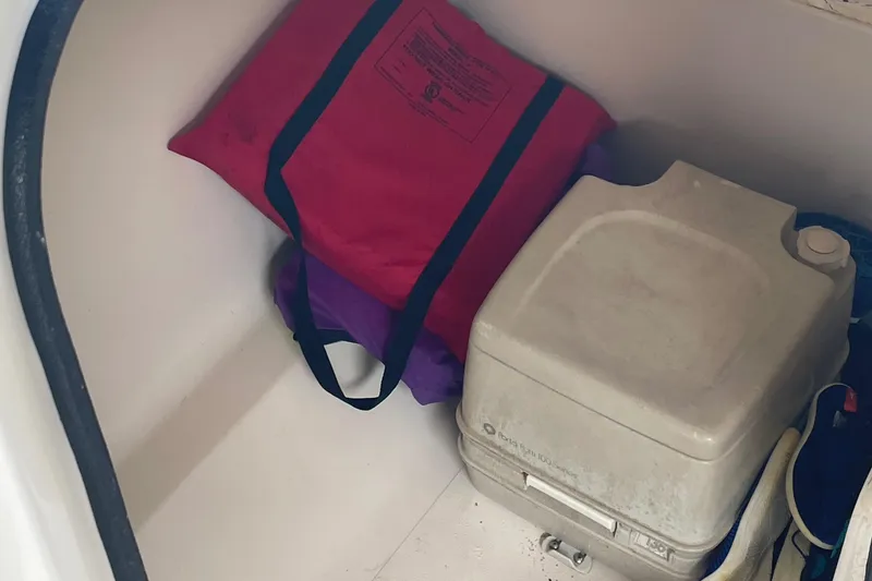 Slide: The Image of Storage compartment in a 2000 Hurricane SunDeck 237 OB with life jacket and portable toilet. - 17