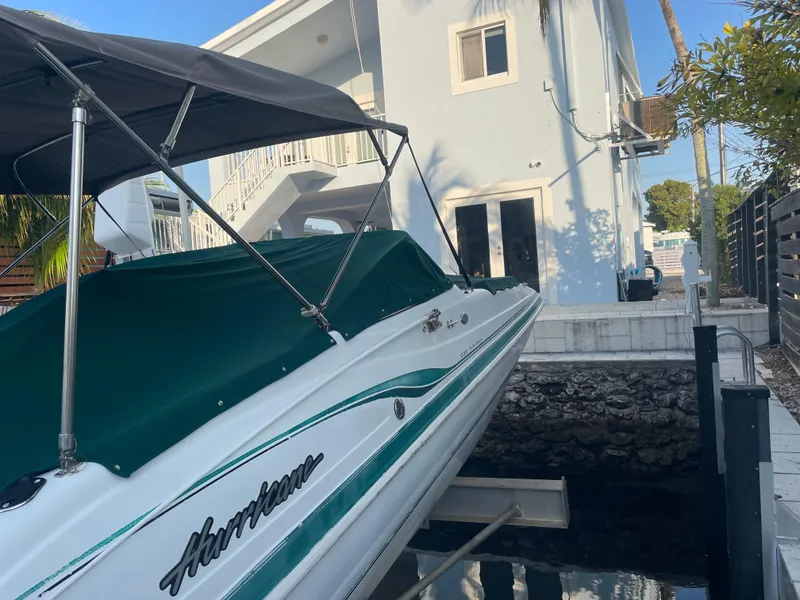 Slide: The Image of 2000 Hurricane SunDeck 237 OB boat docked near a modern white building. - 4